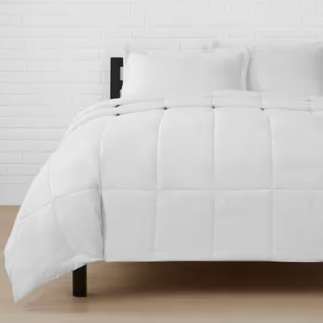 White bedding set with a comforter and pillows on a bed.