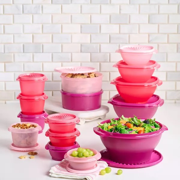 Various sizes of pink and purple food storage containers with some containing food such as salad and grapes.