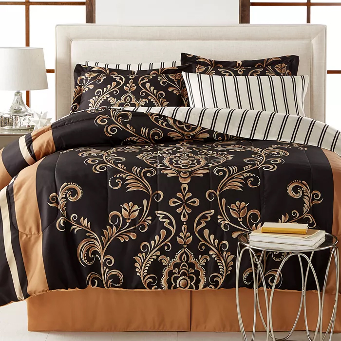Elegant bedding set with black and gold damask pattern, complemented by striped and solid taupe pillows and sheets.