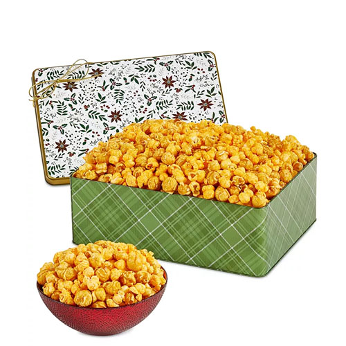 A large green tin and a small red bowl are filled with cheese popcorn, with the tin featuring a decorative lid.