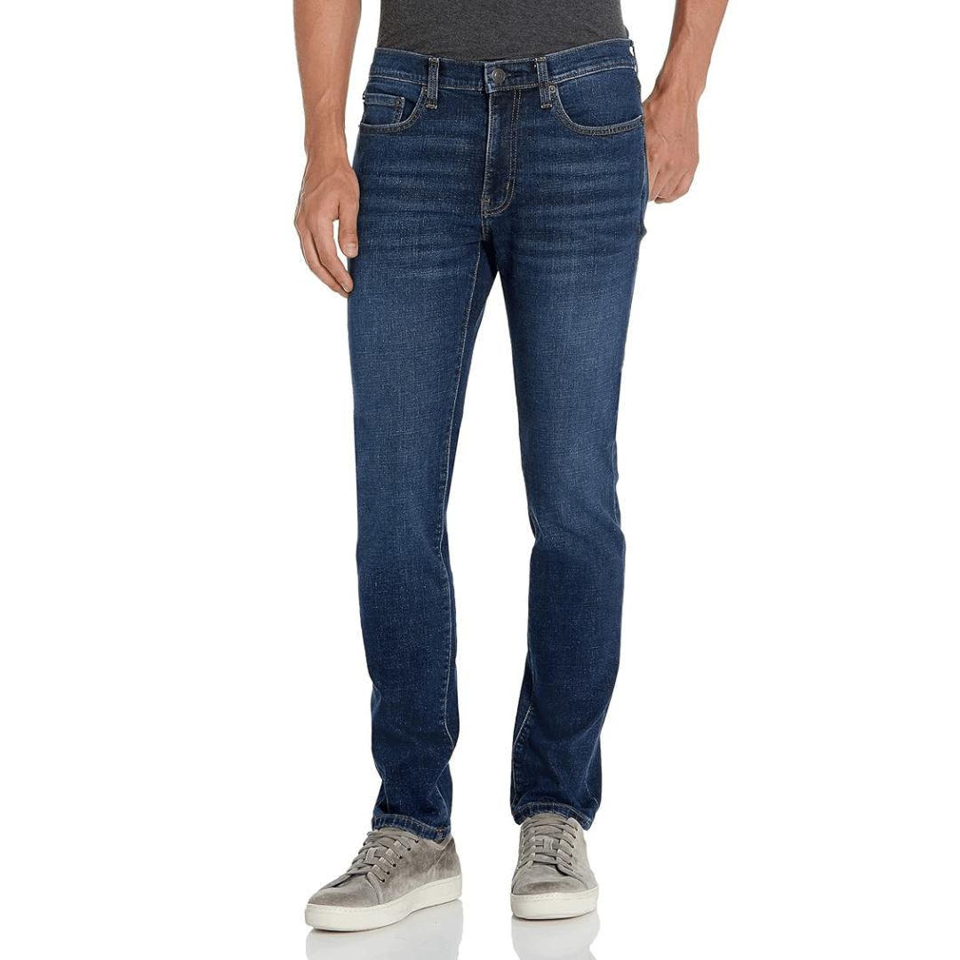 A person is wearing dark wash jeans with a slim fit, paired with a gray t-shirt and gray suede sneakers.