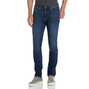 A person is wearing dark wash jeans with a slim fit, paired with a gray t-shirt and gray suede sneakers.