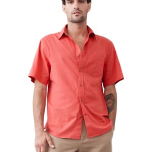 A man is wearing a coral short-sleeve button-up shirt with a chest pocket, paired with beige pants.