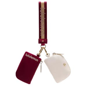 A maroon and white Lululemon wrist strap with two attached zippered pouches.