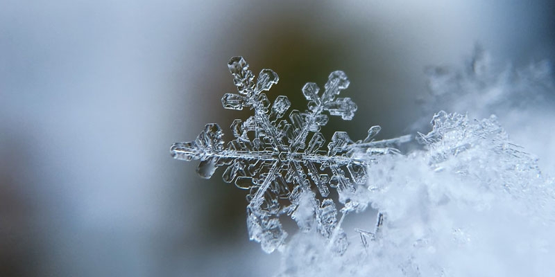 a close up of a snowflake on a blurry blue background