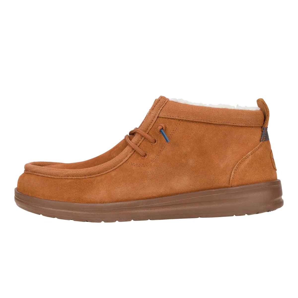 The Hey Dude Wally Mid GripR Warmth is a tan, mid-top shoe with a suede-like finish, featuring lace-up closure and a warm interior lining. Designed for comfort, it has a cushioned sole for enhanced grip.