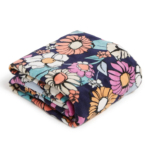 A folded fleece blanket with a floral pattern featuring large, colorful flowers on a dark background.