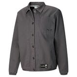 A gray Puma x Cordae shirt jacket featuring button closure, a chest pocket with branding, and adjustable cuffs. It also has a label at the hem and a collared neck design.