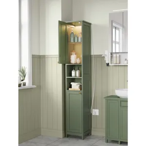 Tall green bathroom cabinet with top and bottom doors, open shelving, and interior lighting, containing various bottles and towels, next to a matching green vanity unit with a white sink.