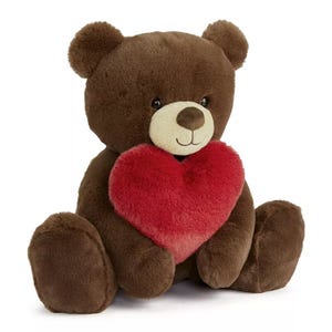 A brown plush teddy bear holding a red heart, approximately 12 inches tall. The bear has a friendly expression and soft, cuddly texture.