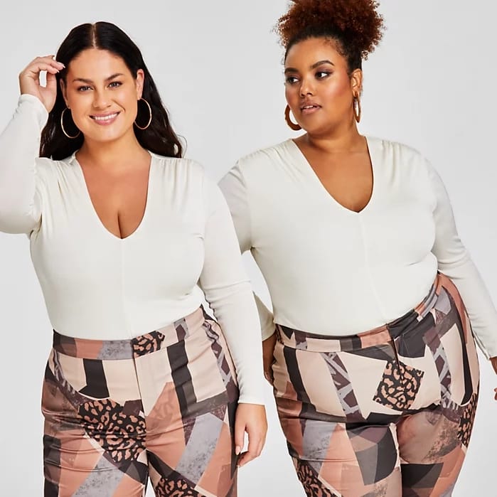 Two women wear matching white long-sleeve tops and geometric patterned pants in shades of brown and pink.