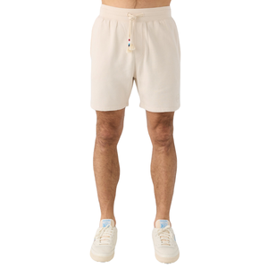 Beige knee-length shorts with an elastic waistband and drawstring, featuring subtle colorful bead details. Worn with light-colored sneakers.
