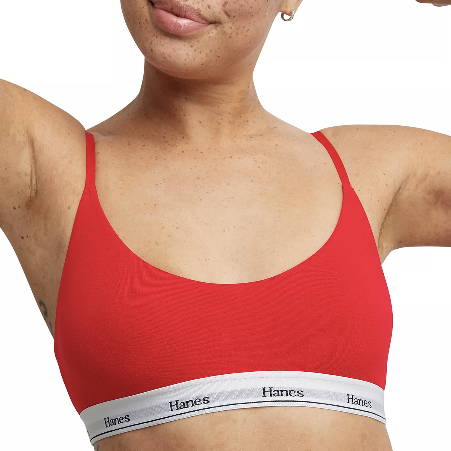 A person is wearing a red Hanes bralette with thin straps and a white band featuring the Hanes logo.