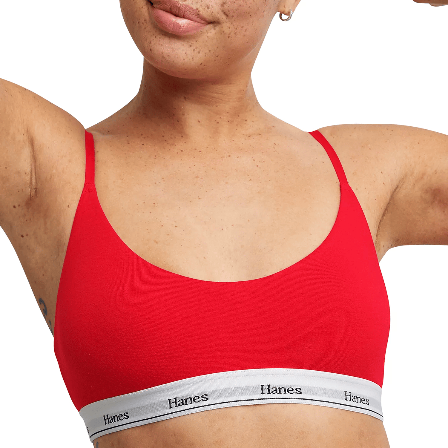 A person is wearing a red Hanes bralette with thin straps and a white band featuring the Hanes logo.