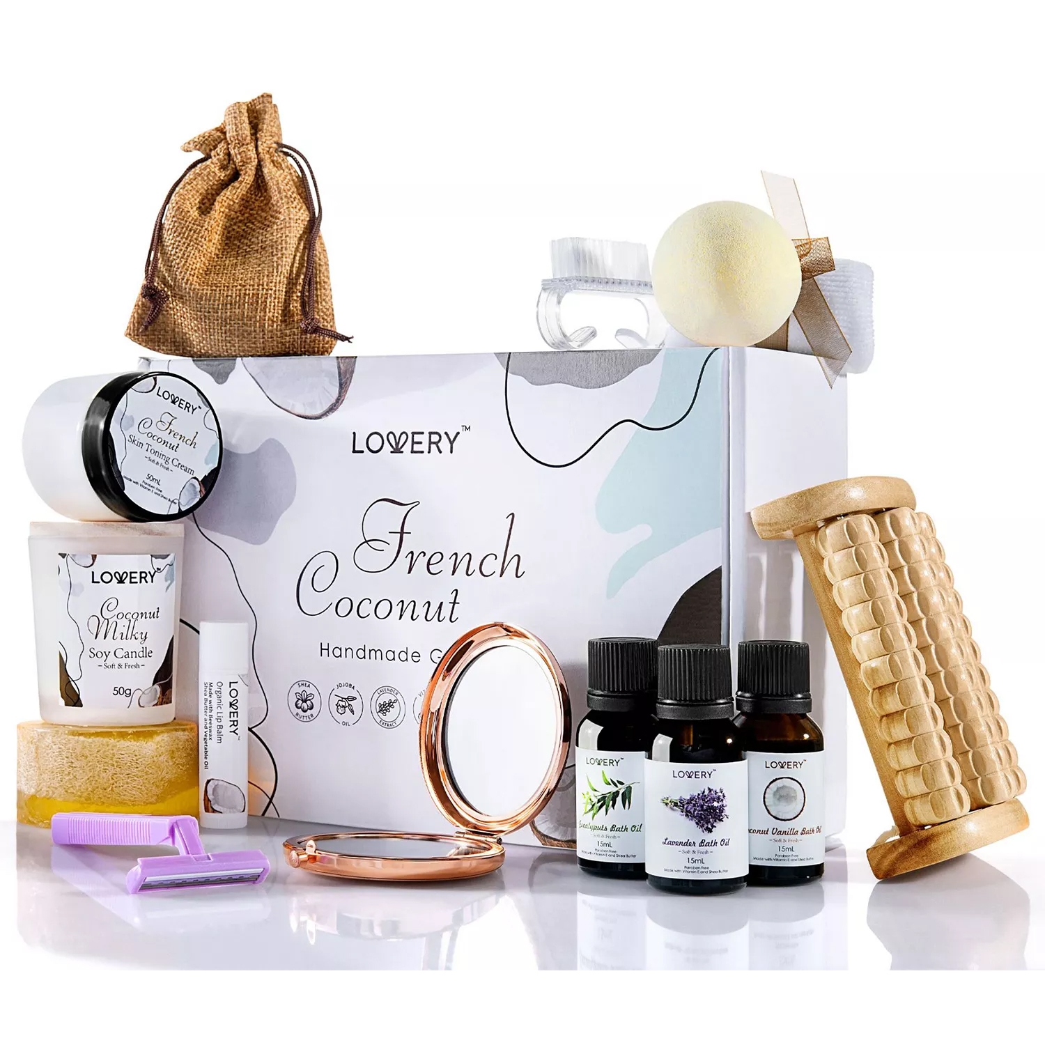 A spa gift set featuring a French Coconut theme includes a soy candle, lip balm, bath oils, a massager, pumice stone, bath bomb, soap, razor, compact mirror, and a small drawstring pouch.