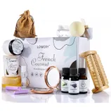A spa gift set featuring a French Coconut theme includes a soy candle, lip balm, bath oils, a massager, pumice stone, bath bomb, soap, razor, compact mirror, and a small drawstring pouch.