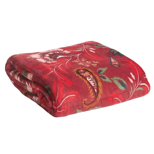 A folded red fleece blanket with a floral and paisley pattern in green, pink, and white hues.