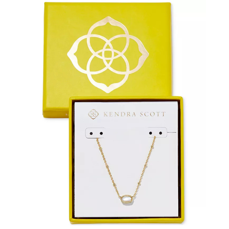 Kendra Scott Boxed Mini Elisa Pendant Necklace features a delicate gold chain with a small, oval-shaped pendant surrounded by crystals, presented in a signature yellow box with a floral emblem.