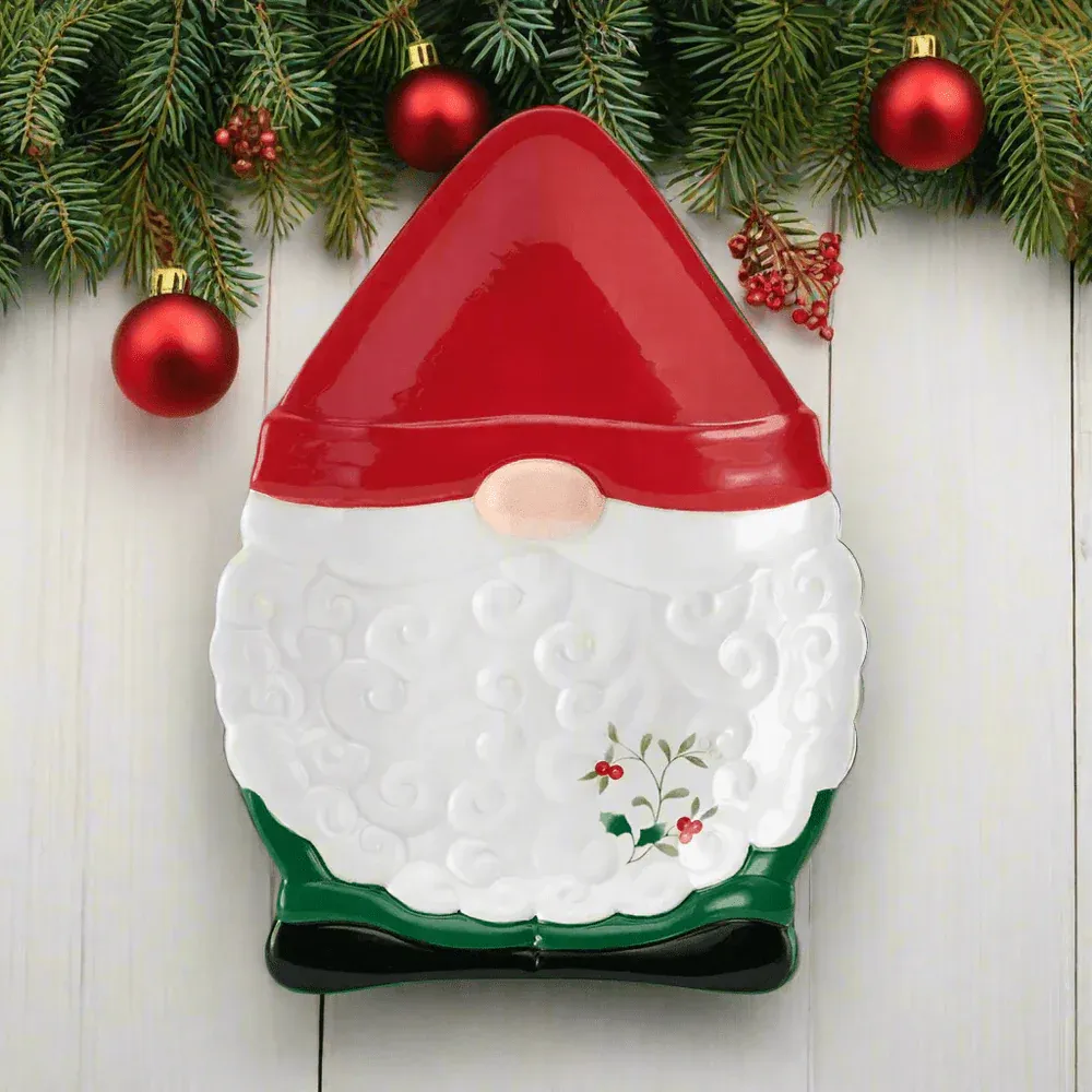 Festive plate shaped like a gnome with a red hat, white beard, and green attire, adorned with a holly design, set against a backdrop of pine branches and red ornaments.