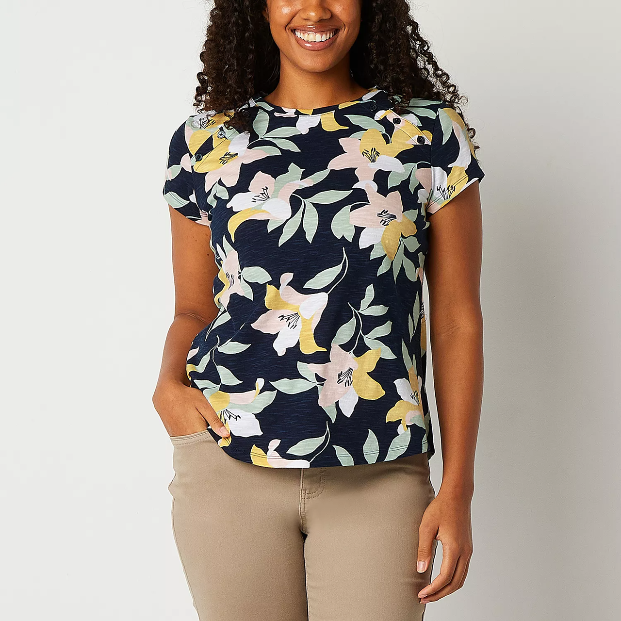 A woman wearing a blue floral print T-shirt and beige pants.