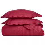 Red quilted bedding set with two pillows featuring scalloped edges and intricate stitching.