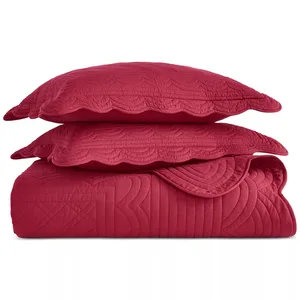 Red quilted bedding set with two pillows featuring scalloped edges and intricate stitching.