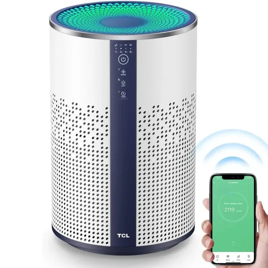 TCL air purifier with a cylindrical design, featuring a digital control panel on the front. A smartphone app on a nearby phone shows connectivity options for controlling the device.