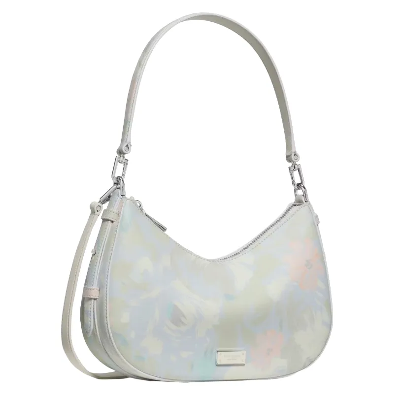 A pastel floral-print handbag featuring a crescent shape, detachable shoulder strap, and a small brand plaque on the front.