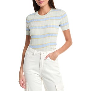 A woman wears a short-sleeve, striped knit top in pastel colors, paired with white high-waisted cargo pants.