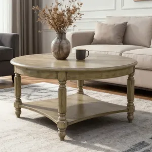Round wooden coffee table with turned legs and a lower shelf, placed in a living room setting with a vase of dried flowers and a mug on top, surrounded by a sofa and an armchair on a patterned rug.