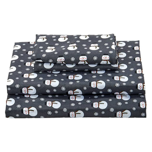 A dark-colored sheet set with a snowman and snowflake pattern, consisting of two pillowcases, a fitted sheet, and a flat sheet.