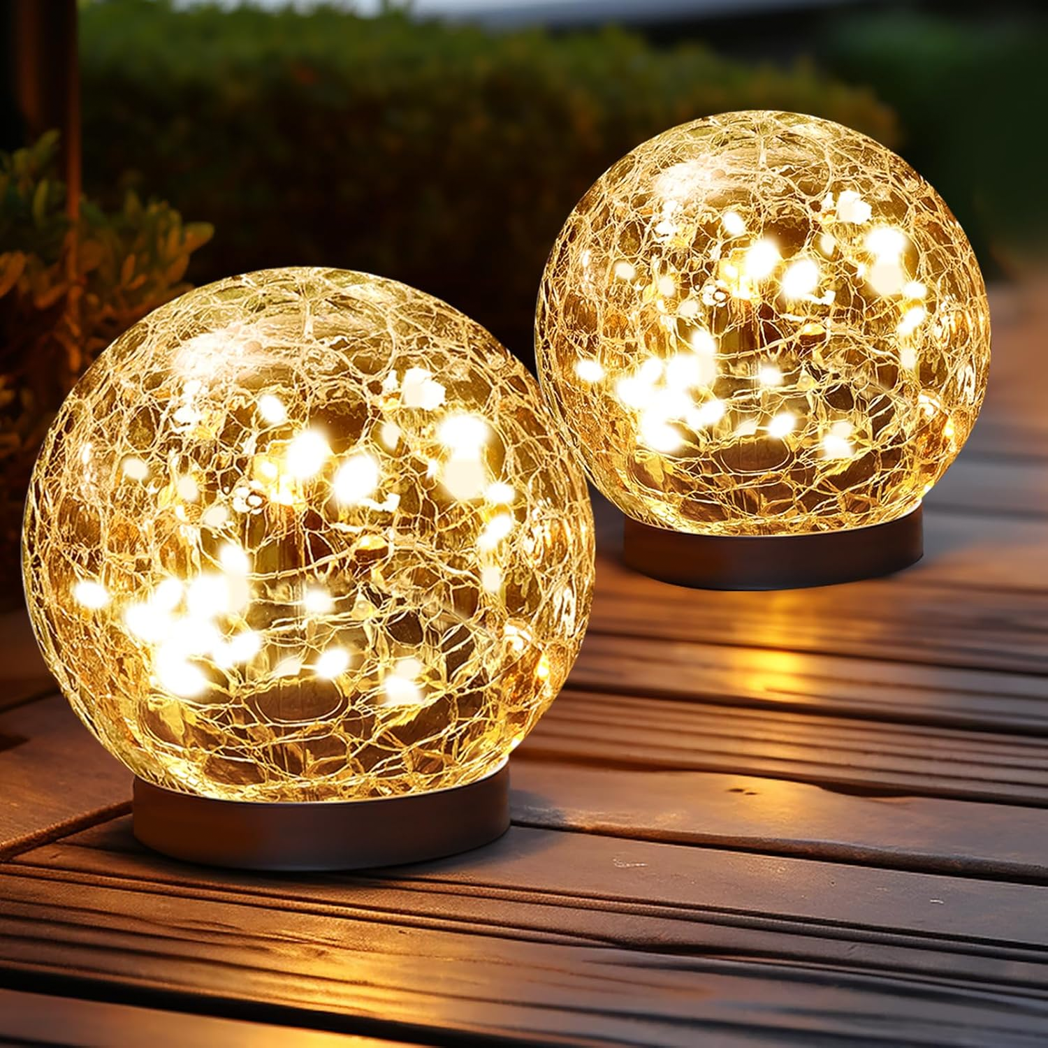 Two spherical crackle glass lights with warm white LED illumination on a wooden surface, creating a cozy outdoor ambiance.