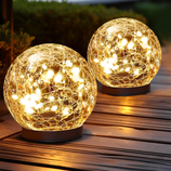 Two spherical crackle glass lights with warm white LED illumination on a wooden surface, creating a cozy outdoor ambiance.