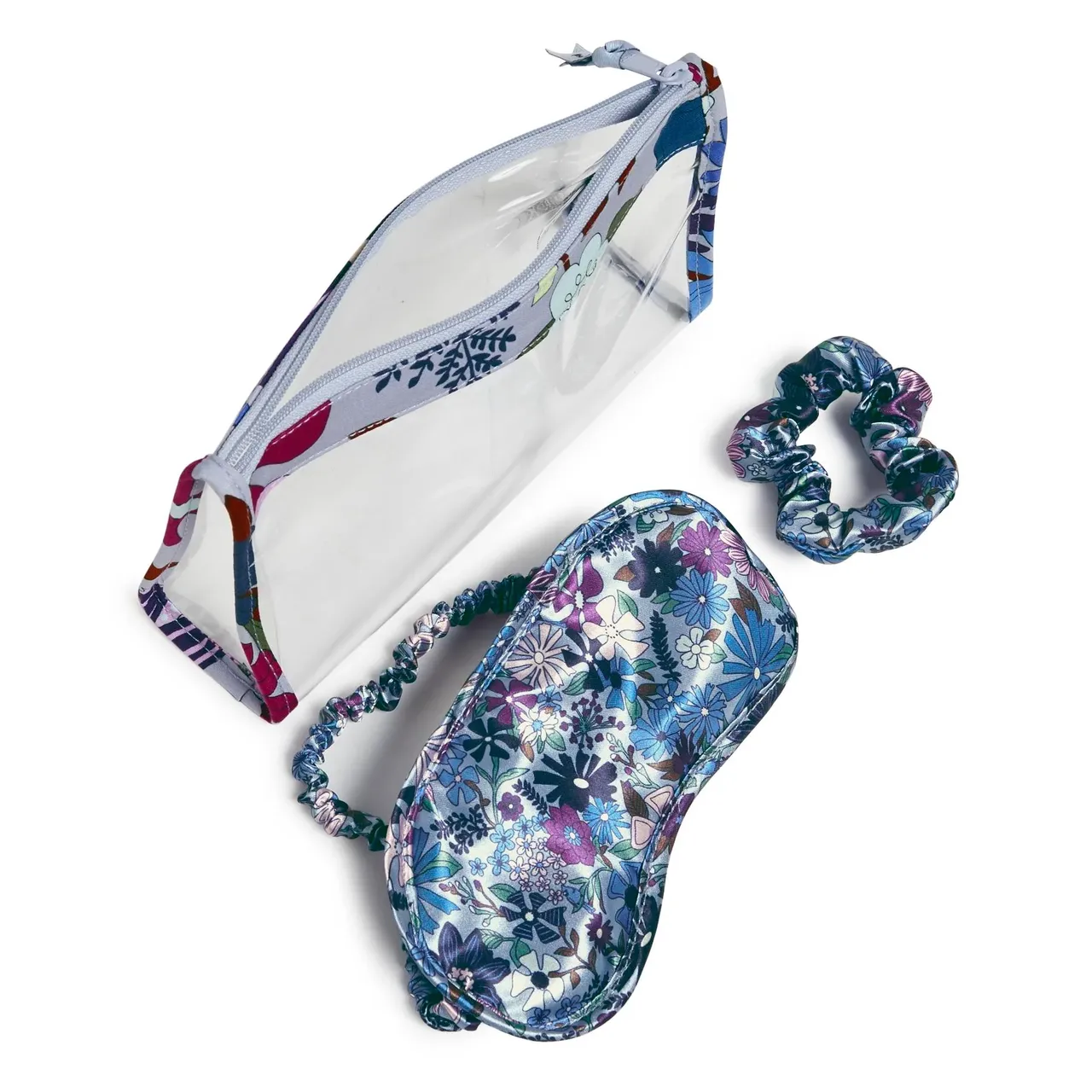 A clear travel pouch, a floral sleep mask, and a matching scrunchie.
