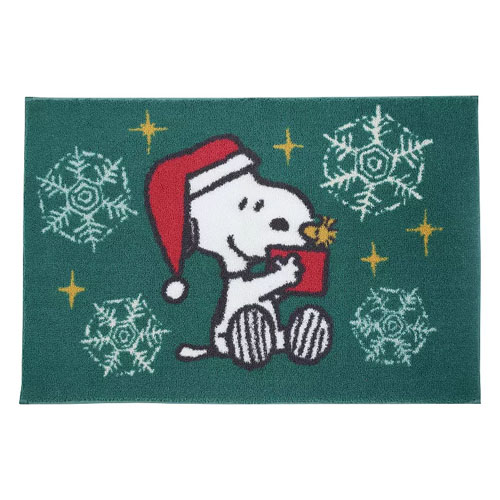 A festive doormat featuring a cartoon dog in a Santa hat, holding a gift with snowflakes and gold stars on a green background.
