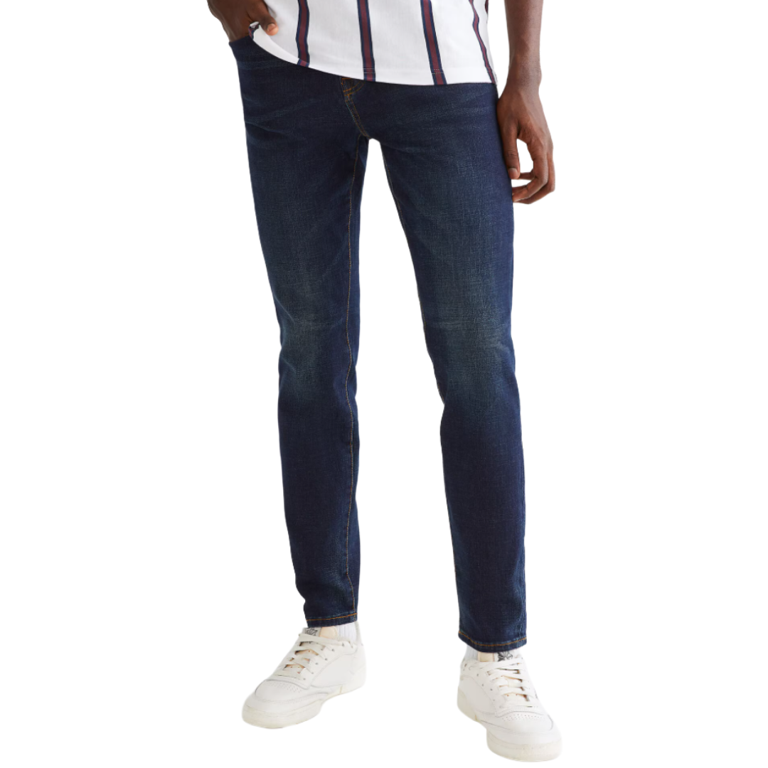Dark blue denim jeans paired with white sneakers and a white shirt with vertical stripes.