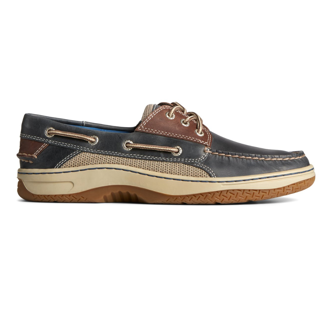 A single boat shoe with brown leather, navy accents, and tan laces on a beige sole.