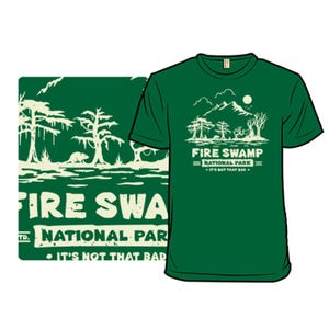Green T-shirt with a design featuring \“Fire Swamp\“ as a national park, including trees and a humorous tagline \“It's Not That Bad.\“