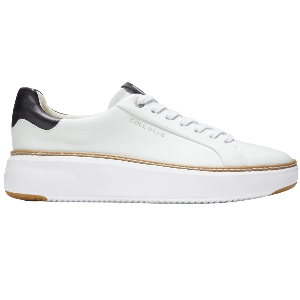 White low-top sneaker with black heel detail, featuring a platform sole and branded with \“Cole Haan\“.