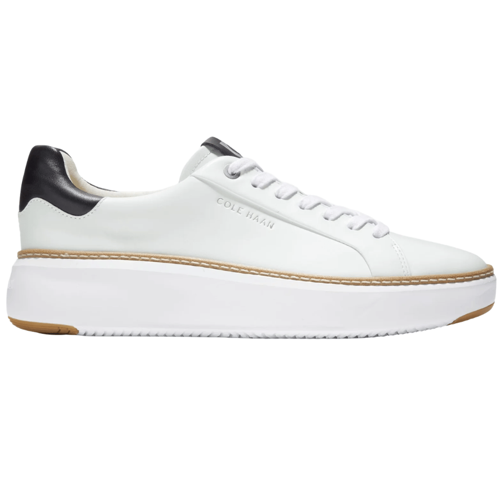 White low-top sneaker with black heel detail, featuring a platform sole and branded with \“Cole Haan\“.