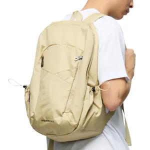 A beige Merrell backpack worn by a person in a white t-shirt, featuring multiple zippered compartments and adjustable straps.