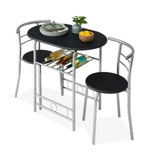 Compact dining set with a black oval table and two chairs featuring silver metal frames. Includes underneath rack storing wine bottles and tabletop decor with a plant and fruit basket. Perfect for small spaces.