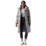 A person wears a long, light gray puffer coat over a light gray shirt with dark gray leggings, gray socks, and white sneakers.