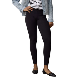 A person is wearing black leggings, a striped shirt, a light denim jacket, and black flats, standing on a wooden floor.