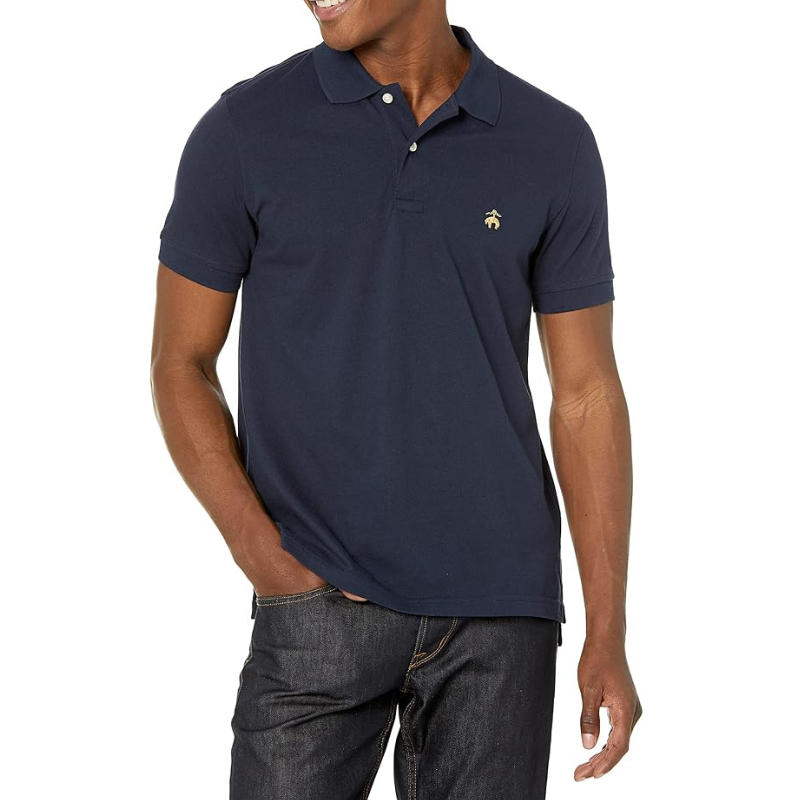 Navy blue solid piqué slim fit polo with a small embroidered logo on the chest, featuring a classic collar, short sleeves, and button placket, paired with dark denim jeans.