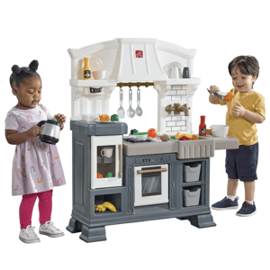 Children playing with a plastic toy kitchen set featuring an oven, stove, utensils, toy food, and accessories.
