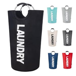 A black collapsible laundry hamper with carrying handles and the word \“LAUNDRY\“ printed in white, accompanied by smaller hampers in blue, red, beige, and grey.