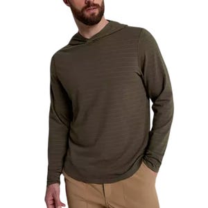 A man wears a VRST Men's Essential Hoodie, featuring a light olive color with fine horizontal stripes, long sleeves, and a comfortable hood, paired with beige pants.