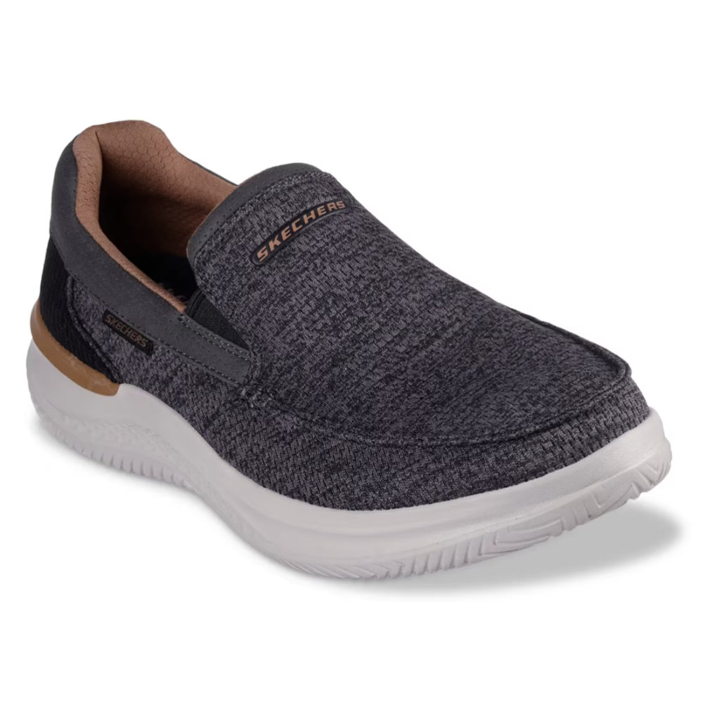 A Skechers slip-on shoe in dark gray with a textured pattern, featuring a white sole and tan interior accents.