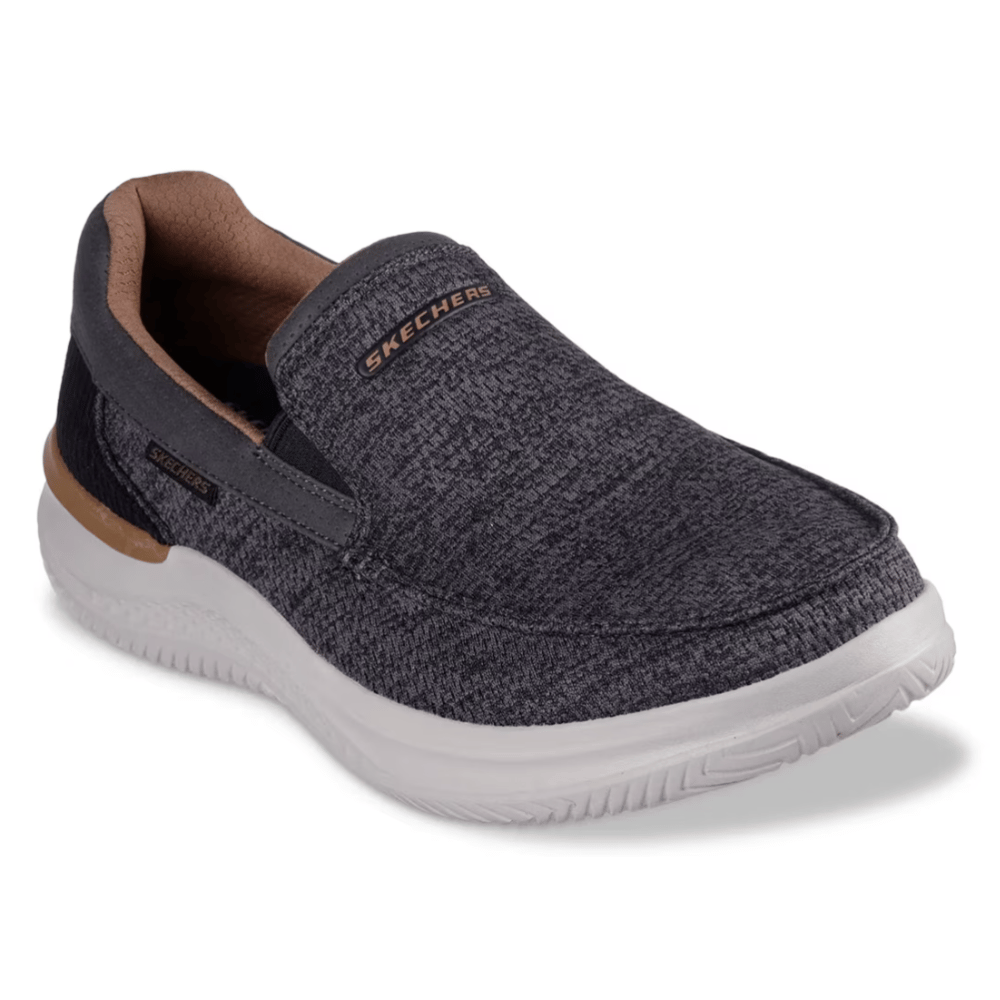 A Skechers slip-on shoe in dark gray with a textured pattern, featuring a white sole and tan interior accents.